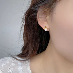 Close-up of a minimalist gold S925 silver stud earring with a white freshwater pearl