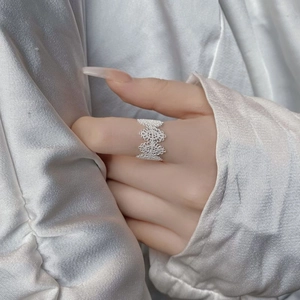 Close-up of vintage hollow lace 925 sterling silver ring worn on model with silk backdrop