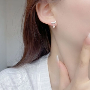 Close-up of minimalist S925 sterling silver bow knot stud earrings worn on ear