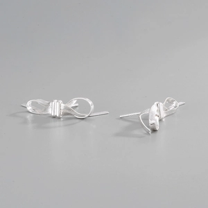 Macro detail of 925 sterling silver bow earrings with woven texture on light background