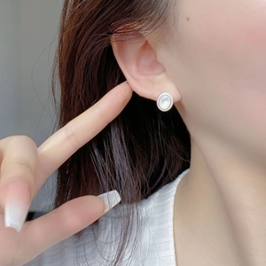 Gros plan de boucles d'oreilles en argent S925 avec nacre blanche sur le modèle