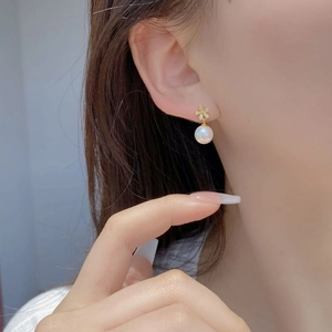 Elegant gold flower S925 silver stud earrings with white pearls on a model ear