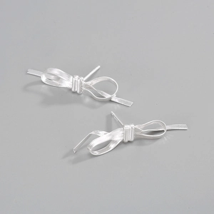 Macro detail of S925 sterling silver bow earrings with brushed metal texture and hallmark