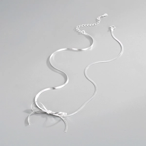Detail of S925 sterling silver flat snake chain necklace with a delicate bow pendant