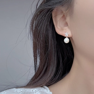 Elegant S925 silver flower stud earrings with white pearls and sparkling zircons on model