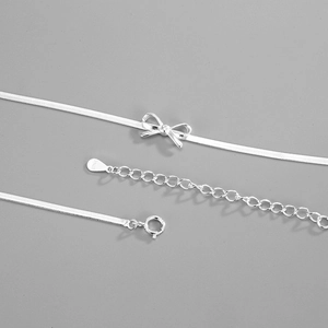 Macro detail of S925 sterling silver stamp on bow necklace with sleek snake chain