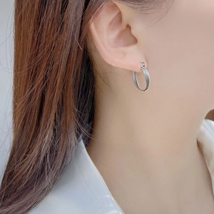 Elegant S925 sterling silver twisted hoop earrings with beaded texture on model