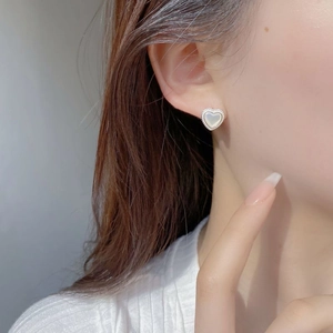 Detail of S925 silver heart stud earrings with white mother of pearl on female model