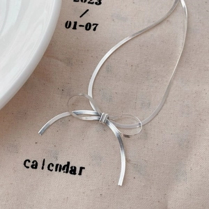 Detailed view of S925 sterling silver blade chain tied in a delicate bow knot style