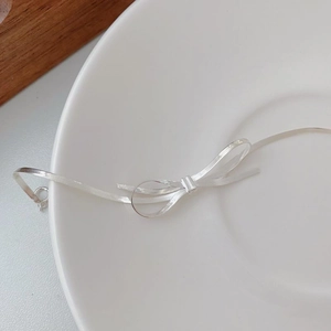 Macro shot of silver bow knot bracelet with flat snake bone chain on ceramic plate