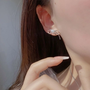 Close-up of silver bow stud earrings with brushed metal finish worn by a model
