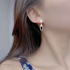 Detailed close-up of matte silver teardrop earrings with black onyx on a female model