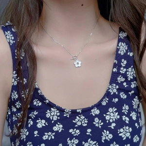 Collana con ciondolo a camelia in argento S925 con chiusura OT sulla clavicola di una donna