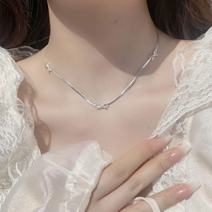 Elegant silver S925 sterling silver bow snake chain necklace worn on a female model