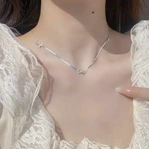 Close-up of S925 sterling silver bow pendants on a flat snake chain necklace