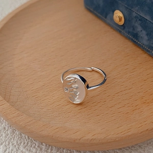 Bague réglable en argent 925 avec motif soleil en nacre sur un plateau en bois