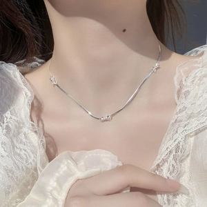 Elegant 925 sterling silver bow necklace with snake chain worn by a female model