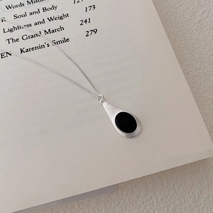 Macro detail of teardrop matte S925 silver necklace with black onyx on book
