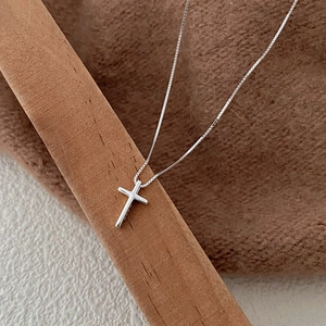Minimalist S925 sterling silver cross pendant necklace displayed on a wooden stand
