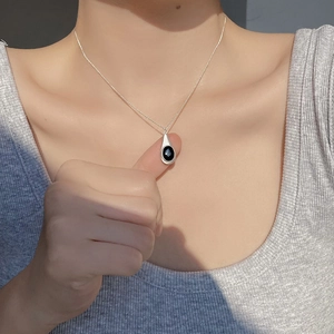 Close-up of S925 sterling silver necklace with black onyx teardrop pendant on model
