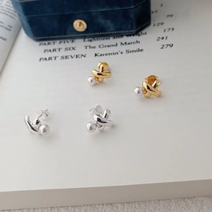 Close-up of gold and silver S925 silver twist knot earrings with pearls on blue velvet