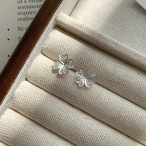 Gros plan de boucles d'oreilles trèfle en argent S925 avec un design filigrane délicat