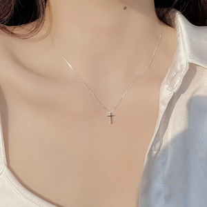 Close-up of minimalist S925 sterling silver cross necklace worn on woman's collarbone