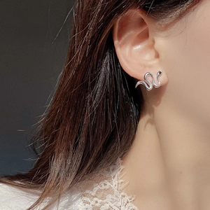 Macro view of S925 sterling silver snake earrings with black zircon eyes on ear
