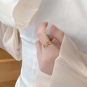 Detail of a wavy 925 sterling silver ring in gold finish on a model's finger