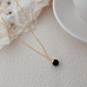 Detail of S925 silver necklace with round black onyx pendant on white lace background