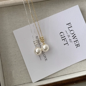 Detailed view of large round pearl pendants on delicate gold and silver chains