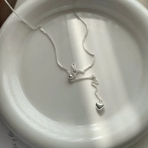 Minimalist 925 sterling silver heart tassel necklace on a white ceramic plate