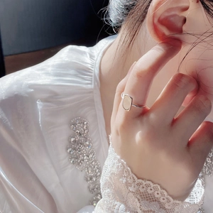 Detail of a geometric S925 silver ring with white mother-of-pearl worn on a finger