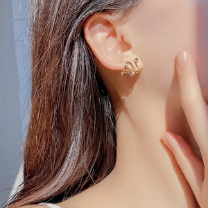 Close-up of gold snake-shaped stud earring worn on model for a trendy heavy-duty aesthetic
