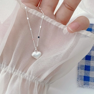 Macro detail of brushed S925 sterling silver heart pendant on a delicate chain necklace