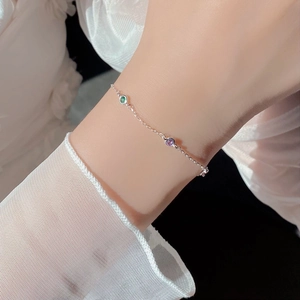 Detail of S925 sterling silver bracelet with green and purple round-cut gemstones