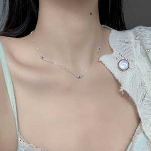 Detail of S925 sterling silver necklace with three tiny colorful gemstones on a model