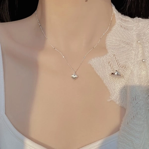 Close-up of S925 sterling silver brushed heart pendant on a delicate chain worn by a model