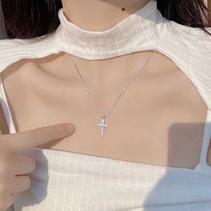 Close-up of S925 sterling silver cross necklace with sparkling diamonds on female neck