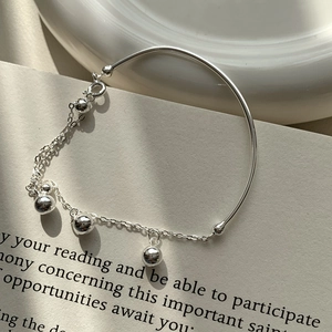 Détail du bracelet en argent sterling S925 avec perles métalliques polies sur un livre