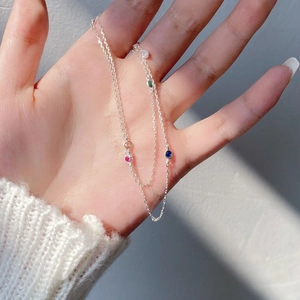 Close-up of S925 silver necklace with four colorful round gemstones in natural sunlight