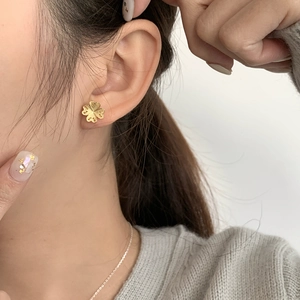 Gros plan d'une boucle d'oreille trèfle dorée aux pétales en forme de cœur