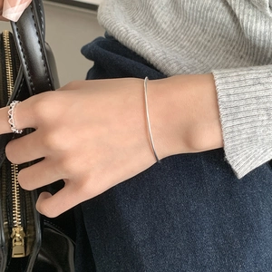 Close-up of minimalist S925 sterling silver beaded bracelet and hollow heart ring on model