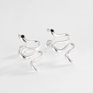 Minimalist S925 sterling silver snake stud earrings with black eye accents on grey background