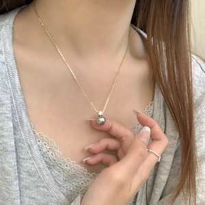 Close-up of a s925 silver necklace with a dark grey pearl pendant on a female model
