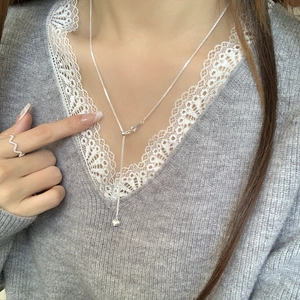 Detail of S925 sterling silver tassel heart necklace and wave ring on a model