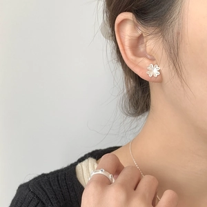 Détail des boucles d'oreilles trèfle et bague en argent S925 sur un mannequin