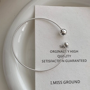Detail of minimalist silver twisted wire cuff bracelet with polished bead terminals
