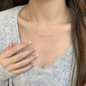Minimalist S925 silver beaded necklace and wavy ring worn on model with soft lighting