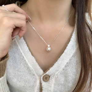 Detail view of round white pearl pendant with sparkling crystal on S925 silver chain